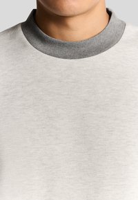 Lichtgrijze sweatshirt met een gestructureerde stof, ronde halslijn met een contrasterende donkergrijze kraag en een eenvoudig, minimalistisch ontwerp.