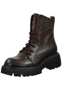 Botas de tobillo de cuero marrón con punta redonda, que presentan una suela de goma negra gruesa y un frente con cordones. Acabado texturizado y ojales de metal.