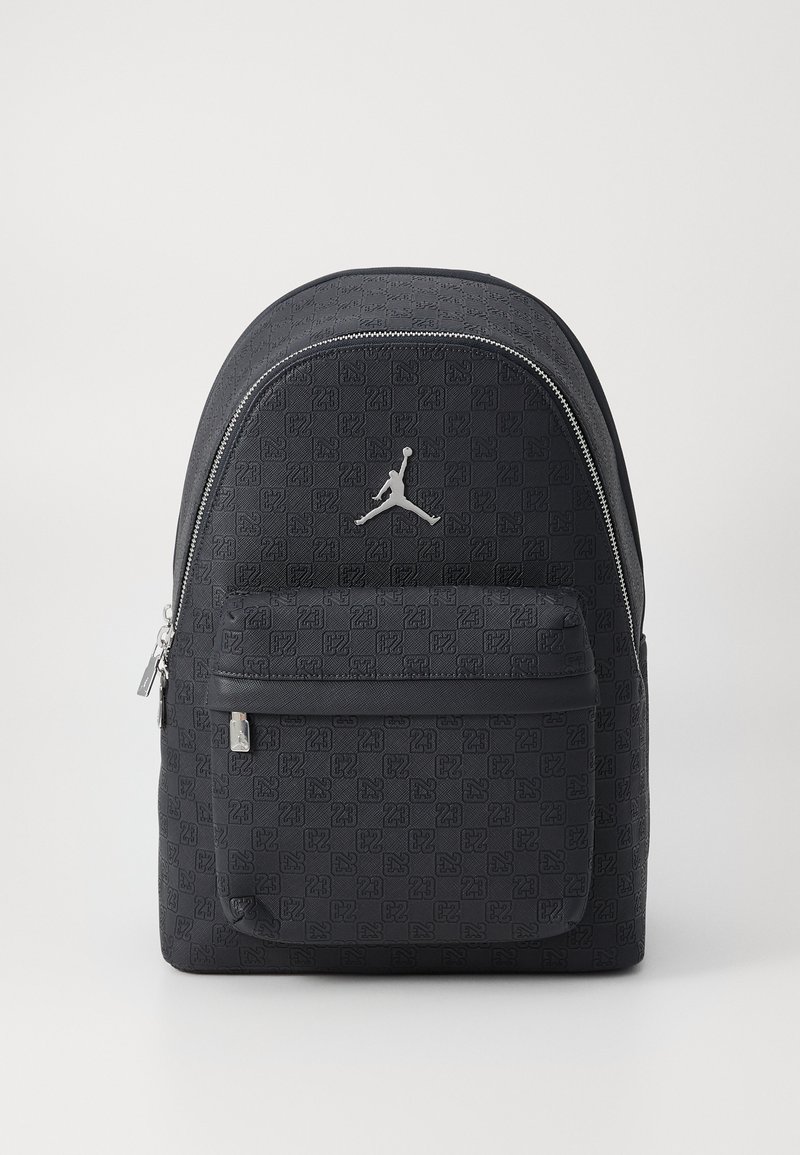 Schwarzer Rucksack mit strukturiertem Muster, ausgestattet mit einer vorderen Reißverschlusstasche und silbernen Beschlägen, verziert mit einem Jumpman-Logo.