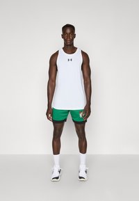 Camisola atlética branca sem mangas com logótipo preto, combinada com calções verdes com um design impresso e detalhes pretos. Meias e sapatos brancos.