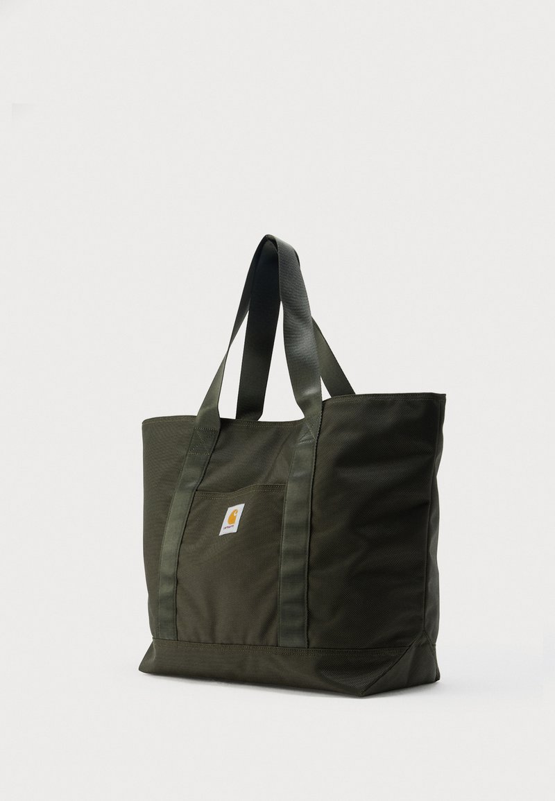 Dark green durable tote bag with dual handles and a front pocket featuring a small square logo label, standing upright on a white background.