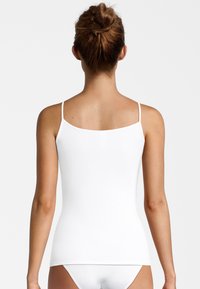White camisole with thin straps, fitted design, and smooth texture. Designed for a snug fit, suitable for layering or casual wear.