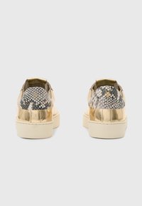 Sneaker metallici dorati con un accento in pelle di serpente texturizzata sul tallone. Presentano la punta rotonda e una suola in gomma piatta per stabilità.