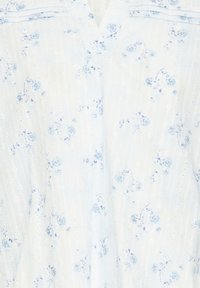 Tissu blanc avec un petit imprimé floral bleu clair et de subtiles rayures verticales ajourées, avec un détail en col en V.