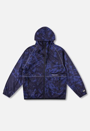 Marineblå hættejakke med lilla camouflageprint, lynlås foran, to lynlåslommer, elastiske manchetter og "Riviera Projects"-logo på brystet.