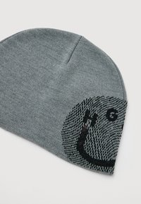 Szary dziany beanie z okrągłym czarno-szarym wzorem oraz literami "H" i "G" z jednej strony na białym tle.