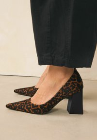 Cipele s visokom potpeticom u leopard uzorku od teksturirane tkanine, s oštrim vrhom i suženim blok potpeticom; boje su crna i smeđa.
