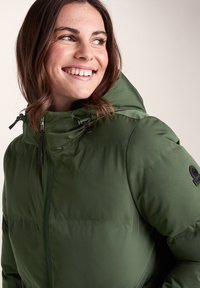 Green puffer jacket with a high collar and hood. Features adjustable drawstrings and a black logo patch on the sleeve. Smooth texture.