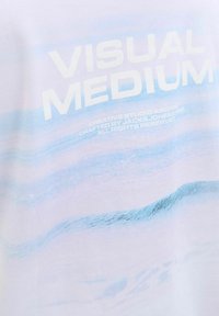 Balta medvilninė marškinėliai su švelniu mėlynu bangų raštu. "VISUAL MEDIUM" ryškiai atspaudintas storu baltytu šriftu.