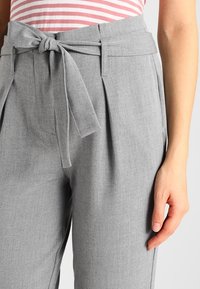 Grijze high-waisted broek met een strikceintuur, voorzien van plooien aan de voorkant en zijzakken, gemaakt van een gladde, lichtgewicht stof.