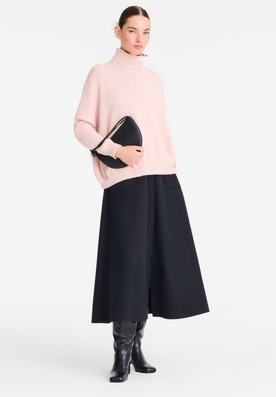 Light pink oversized knitted sweater with a high collar, paired with a long black skirt and knee-high black leather boots. Black clutch bag included.