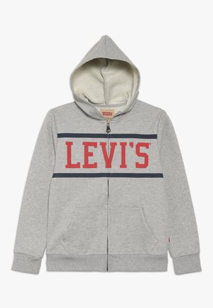 Szara bluza z kapturem zapinana na zamek, z przednimi kieszeniami, miękką podszewką i napisem "LEVI'S" w dużych czerwonych literach między dwoma granatowymi paskami na wysokości klatki piersiowej.