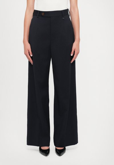 Zwarte wijde broek van een gladde stof, met een knoopsluiting en riemlussen. Geen zichtbare patronen, rechte zoom.
