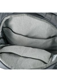 Interior de mochila gris con dos compartimentos, con un forro gris texturizado y una sección acolchada para protección. Cierre con cremallera visible.