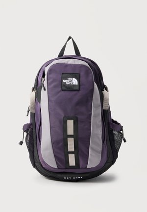 Fialový a sivý batoh The North Face Hot Shot s prednými slučkami, sieťovanými bočnými vreckami a horným držadlom na prenášanie.
