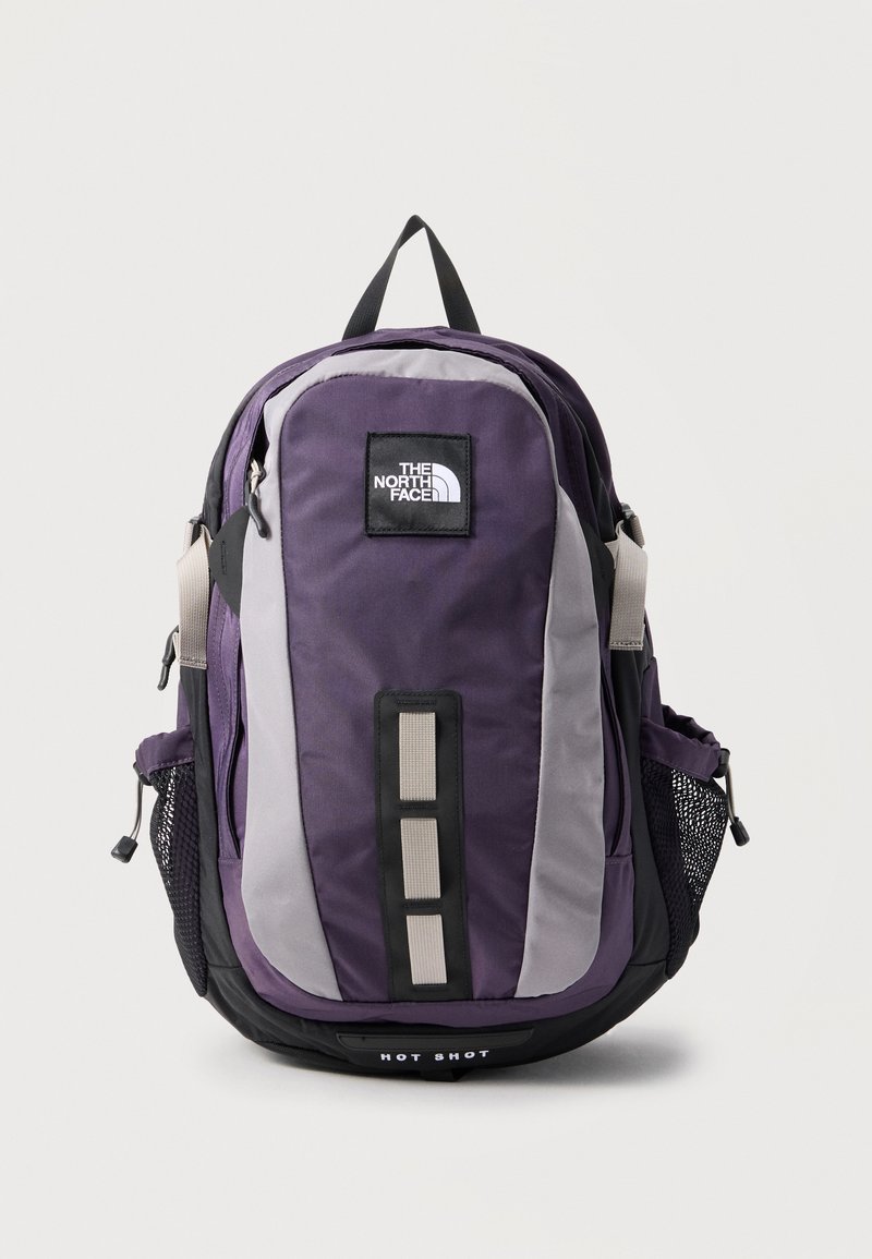 Μωβ και γκρι σακίδιο The North Face Hot Shot με μπροστινές θηλιές, δίχτυ πλαϊνές θήκες και επάνω χερούλι μεταφοράς.