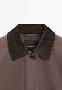 Cappotto marrone con colletto in corduroy, chiusura con bottoni e texture di tessuto liscia. L'etichetta interna reca la scritta "Massimo Dutti."