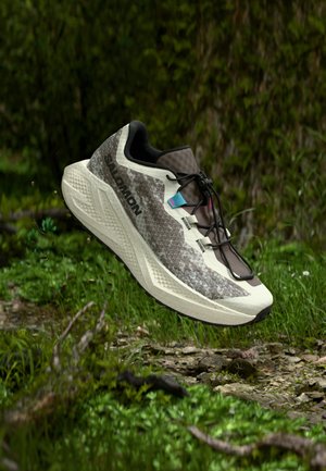 Lightweight running shoe with a textured, brown and beige upper, black accents, and a cushioned white midsole, designed for outdoor terrain.
