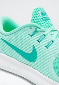 Sneakers Nike turchesi con parte superiore in rete testurizzata, design a coste e suola bianca. Presentano il famoso logo swoosh di Nike sul lato.