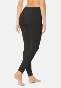 Leggings noirs avec une texture lisse, une taille haute et un design à longueur de cheville. Présente un bord festonné subtil au niveau de la taille.