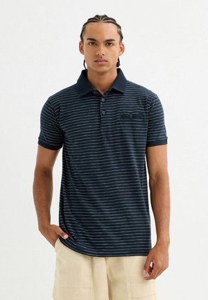 Polo de rayas marinas con mangas cortas, con botones en la parte delantera y cuello texturizado. Presenta un pequeño bolsillo en el pecho y está hecho de tela de algodón suave.