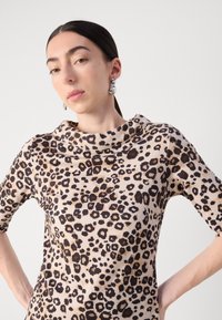 Leopard print top with a cowl neck, short sleeves, and a soft fabric. Features a light beige base with dark brown spots.