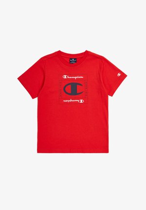 T-shirt en coton rouge avec un logo Champion noir et blanc centré sur le devant, à manches courtes et à col rond.