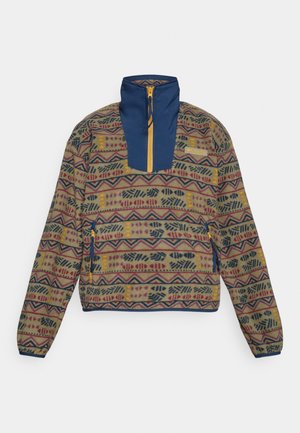 Veste à enfiler multicolore avec un corps en polaire à motifs, un col bleu marine et un panneau de poitrine, fermeture éclair et poche latérale avec accent jaune.