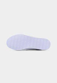 Λευκή σόλα αθλητικού παπουτσιού με οριζόντιες ραβδώσεις και επαναλαμβανόμενο ανάγλυφο μοτίβο κειμένου σε απλό ανοιχτό γκρι φόντο.