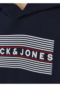 Sudadera navy con un diseño a rayas blancas y rojas, con el texto "BRICK&JONES" en letras blancas en negrita. Tejido suave, corte casual.