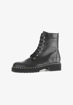 Bottines noires en cuir avec un design à lacets, bout arrondi, accents en métal doré et semelle épaisse avec des détails cloutés.