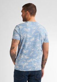 Světle modré tričko s bílým květinovým vzorem, krátké rukávy a kulatý výstřih; bavlněný materiál s měkkou strukturou.