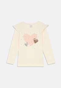 Cream long-sleeve toddler shirt with ruffled shoulder details, pink heart print, and two smaller silver and gold sequin hearts on front.