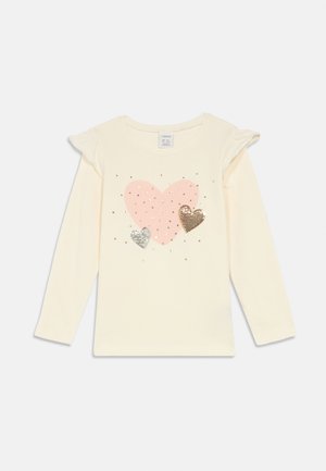 Camisola de manga longa para criança em creme, com detalhes em ruffles nos ombros, estampado com corações rosas e dois corações menores em lantejoulas prateadas e douradas na frente.