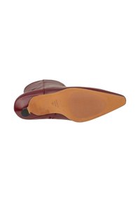Stivale alla caviglia in pelle borgogna con punta affusolata, texture liscia e suola piatta in caucciù marrone con scanalature orizzontali e grip sul tallone posteriore.