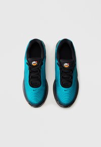 Pari turkoosi- ja mustia Nike Air Max -tennareita nähtynä ylhäältä vaalean valkoista taustaa vasten.