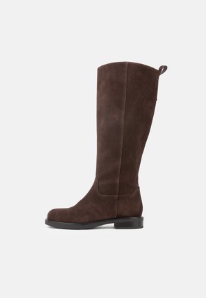 Stivale marrone in suede alto alla caviglia con tacco basso nero e linguetta posteriore, mostrato di profilo su sfondo bianco.
