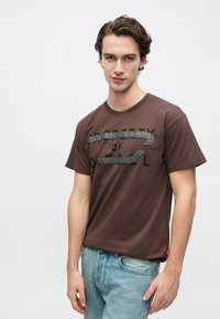 Καφέ βαμβακερό t-shirt με γραφικό σχέδιο και το κείμενο «PROPERTY OF» σε μαύρο, διακοσμημένο με γκρι οριζόντιες ρίγες, με στρογγυλή λαιμόκοψη.