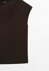 Ærmeløs mørkebrun top med rund halsudskæring, der viser den øvre front og en tøjmærkat inde i kraven.