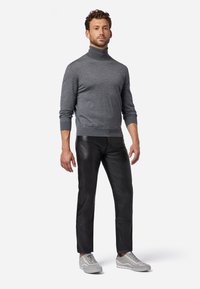 Grijze coltrui gecombineerd met zwarte leren broek en grijze sportschoenen; gestructureerde stof en getailleerd ontwerp.