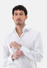 Camicia a quadri bianchi con colletto punta, polsini con bottoni e maniche lunghe. Il tessuto appare liscio con una leggera lucentezza.