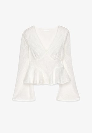 White peplum top with a deep V-neck and long, flared sleeves. Embroidered floral pattern throughout, made from lightweight, textured fabric.