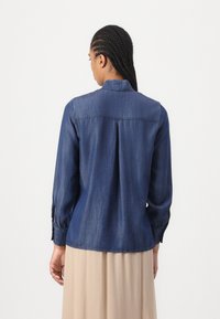 Dunkelblauses Denimhemd mit Kragen, langen Ärmeln und gerafften Manschetten. Verfügt über einen geraden Schulterbereich und eine lockere Passform.