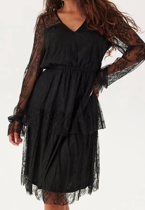 Czarna koronkowa sukienka z długimi, przezroczystymi rękawami, dekoltem w kształcie litery V, elastyczną talią oraz warstwową spódnicą zdobioną delikatnymi koronkowymi detalami.