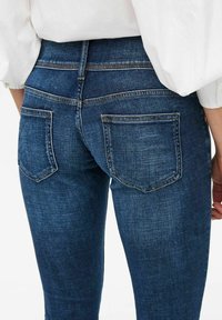 Mörkblå denimjeans med en figursydd design, midjemått mitt på höften och två bakfickor med kontrastsöm. Mjuk textur med klassisk känsla.