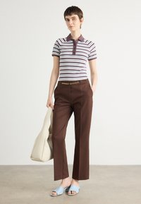 Polo a righe in azzurro chiaro e marrone, pantaloni marroni con cintura a catena dorata, sandali azzurri chiari e borsa a spalla color crema.