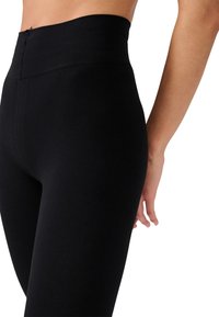Leggings neri a coste con vita alta, dal texture morbido, caratterizzati da una gonna stretta che aderenza bene alle gambe.