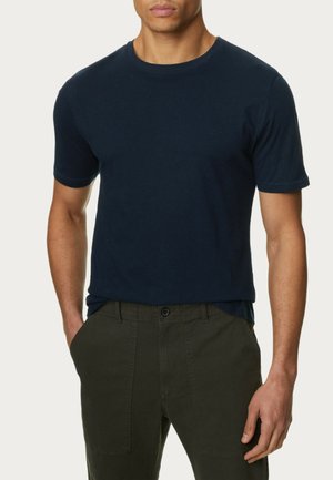 Marineblauwe katoenen t-shirt met ronde hals en korte mouwen. Glad textuur, slim fit, gecombineerd met olijfgroene broek met voorzakken.