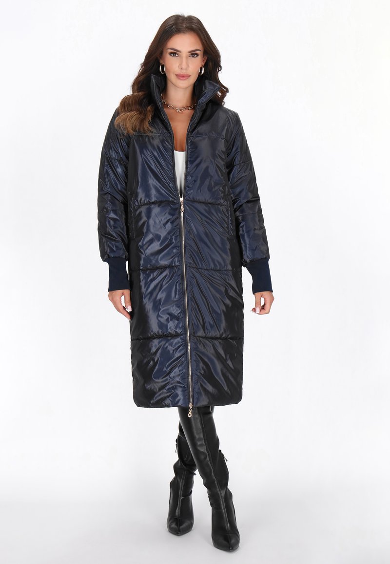 Marineblå dunjakke med lynlås foran, høj krave og vandret syninger, med ribbede manchetter og knælang længde.