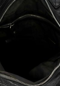 Interno di una borsa in pelle nera con rivestimento in tessuto, dotata di una cerniera argentata e di una piccola tasca. L'interno è scuro con visibilità minima.